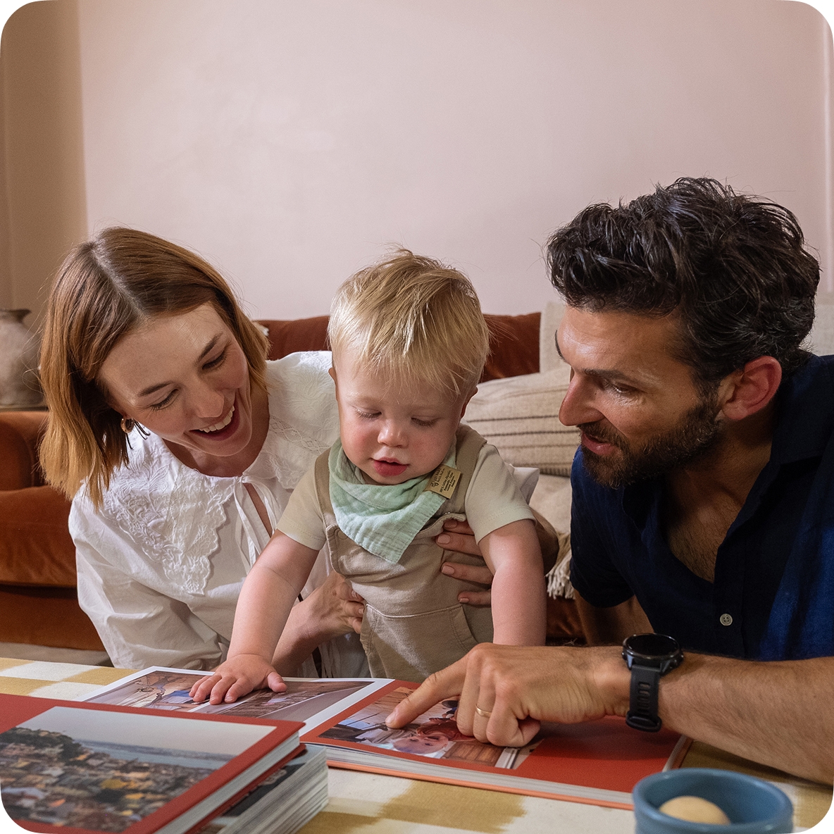 Young parents look through a baby photo book while cuddling their toddler son